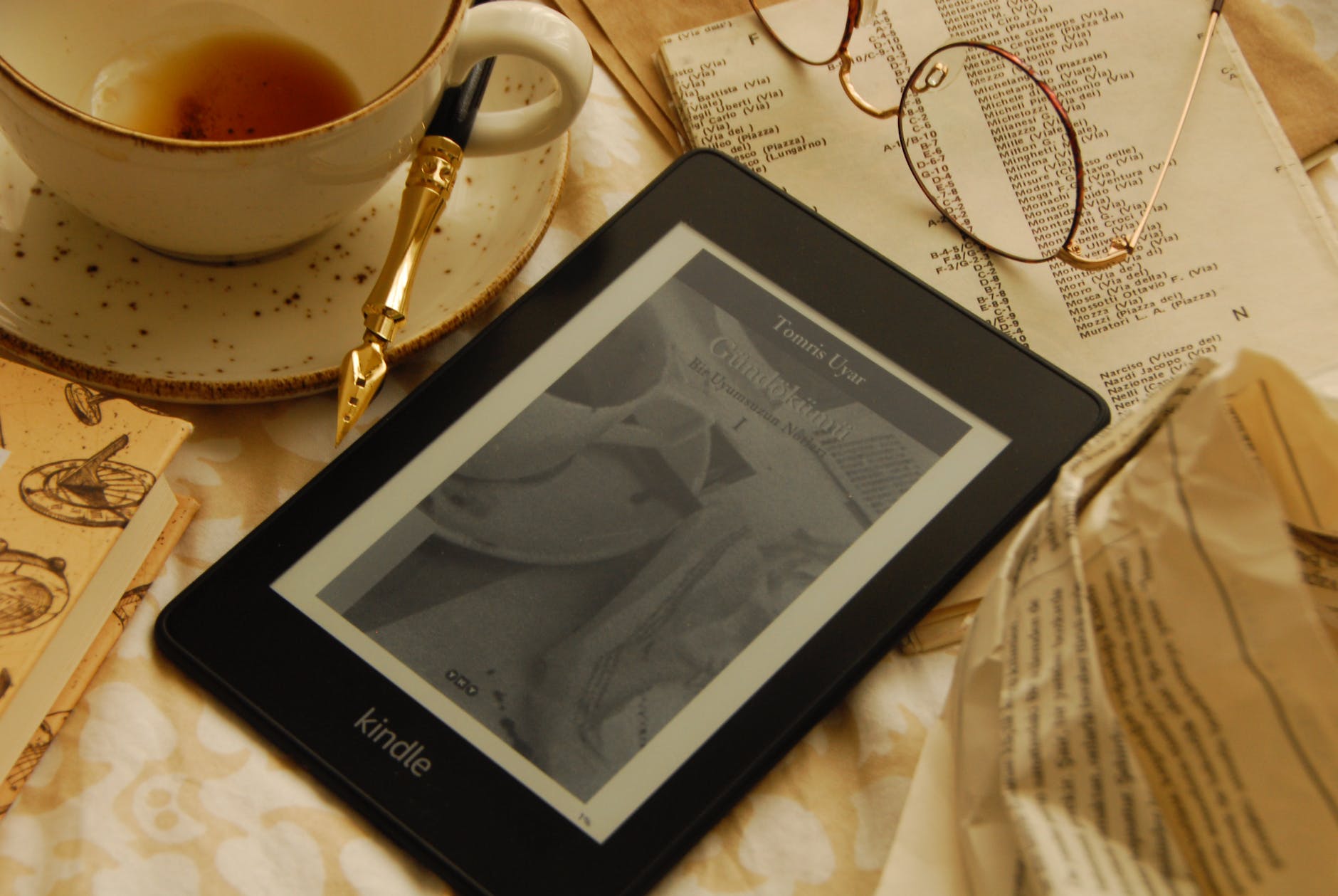 a kindle electronic reading device beside a cup of coffee